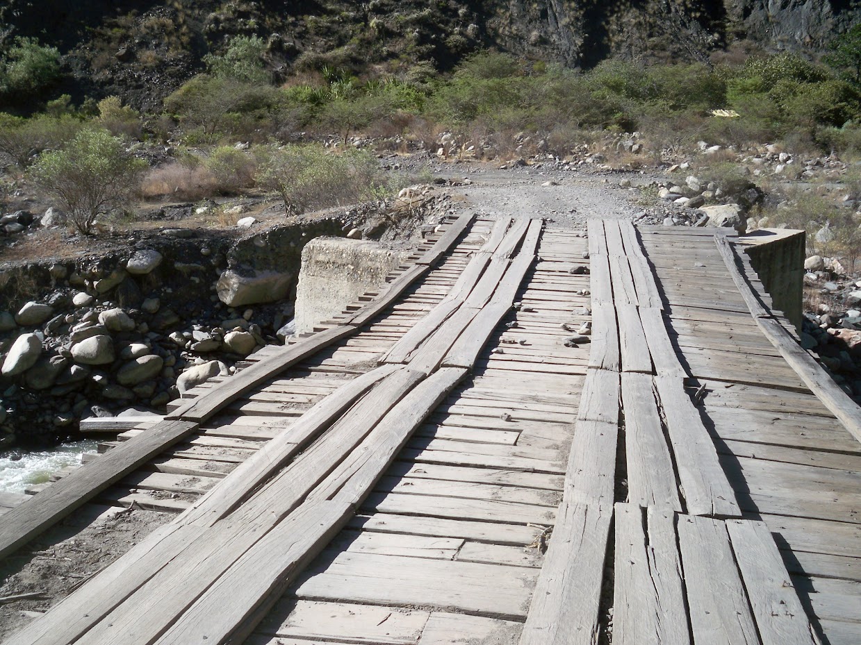 A simple wooden bridge crossing a river near Mollepata, Peru
