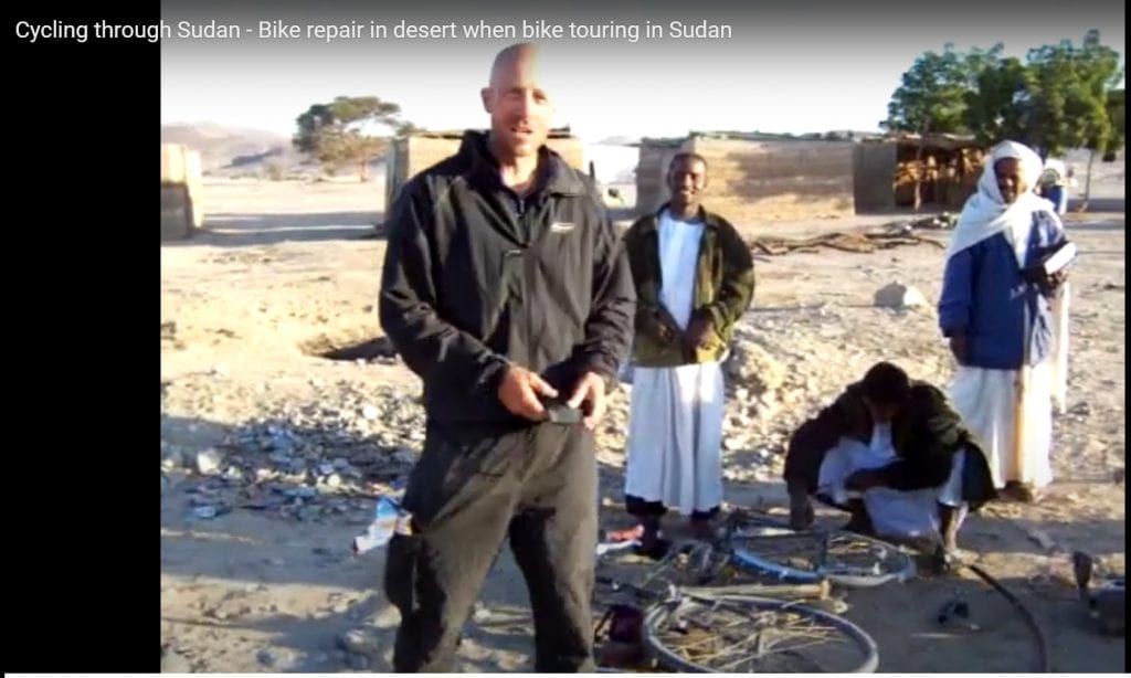 Dave cycling in Sudan fixing a broken bicycle rack