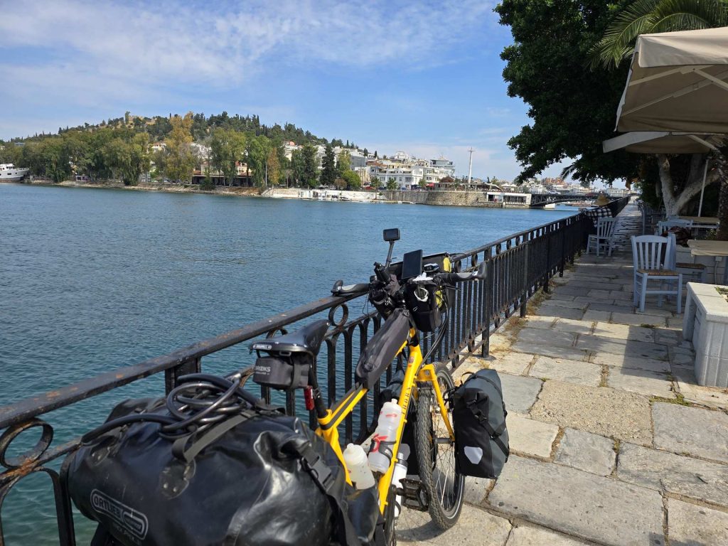 A loaded yellow Thorn Nomad Mk2 touring bicycle with panniers parked along a waterfront promenade on Evia island, Greece